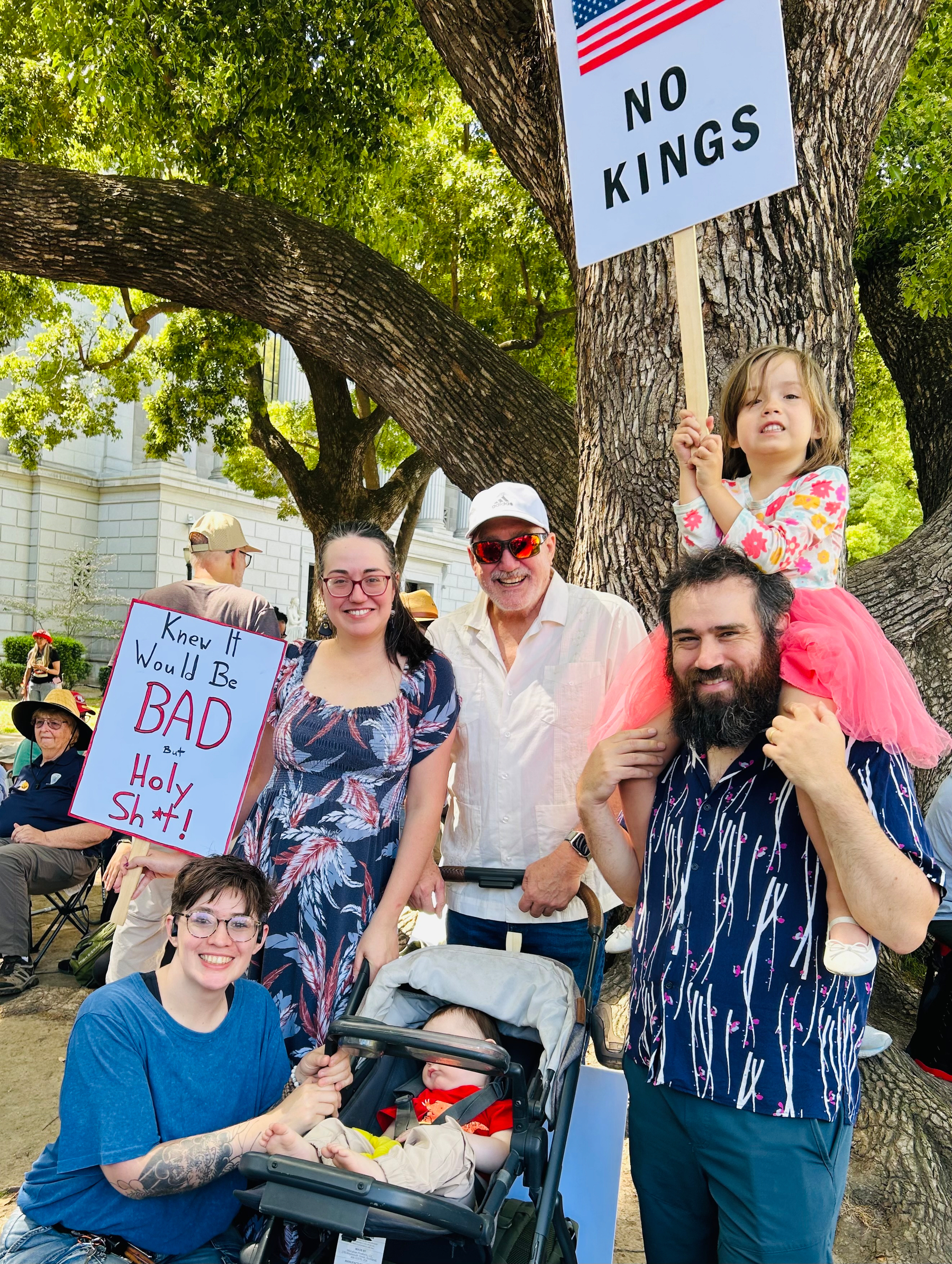 A family (four adults, two kids) at a political protest holding signs 